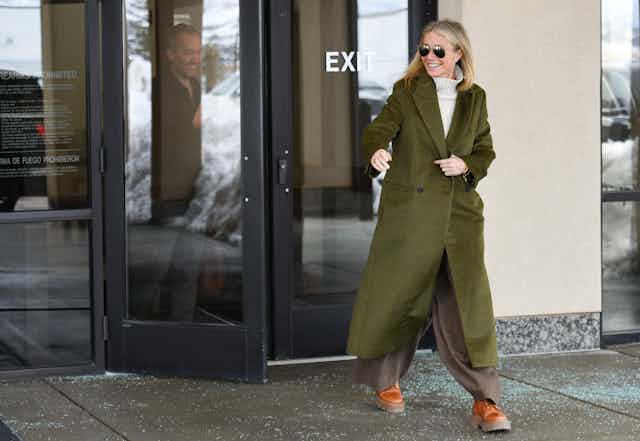 blonde woman in sunglasses exits a building