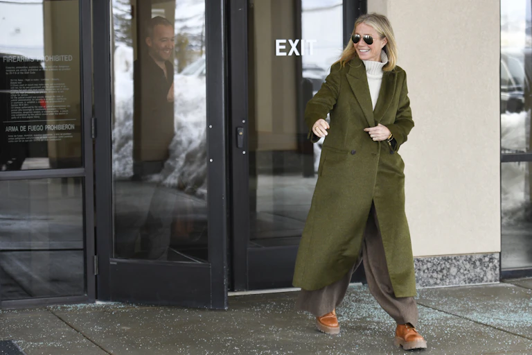 blonde woman in sunglasses exits a building
