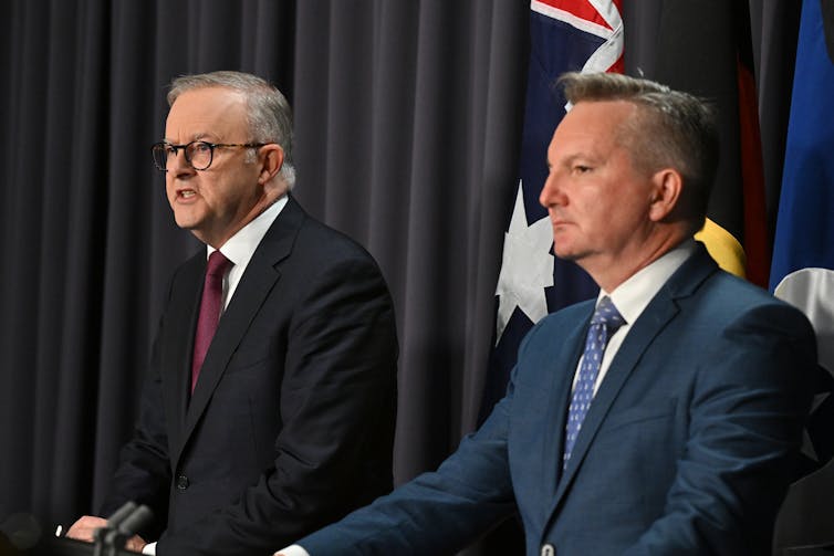 two men in suits stand at lectern