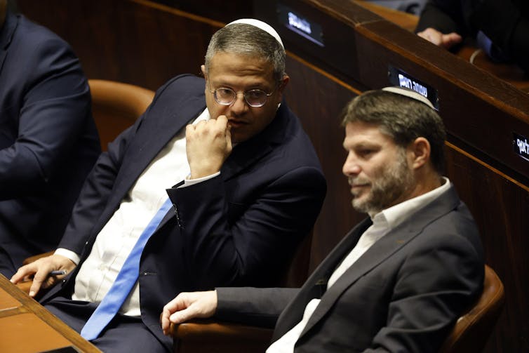 Two Israeli politicians wearing skull caps sitting in the Israeli Knesset.