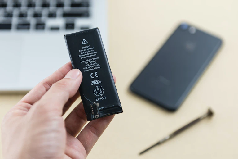 Una mano sostiene una batería de teléfono usada.