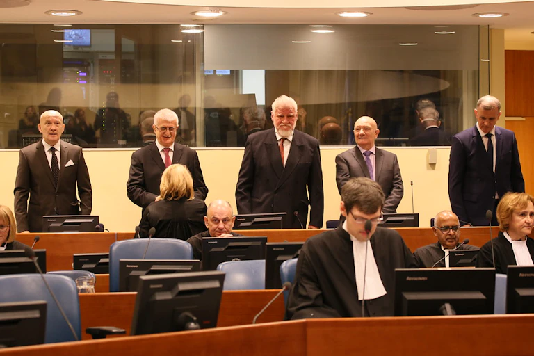Cinq hommes se tiennent debout face à des magistrats