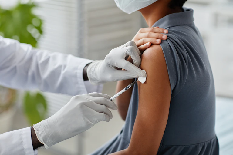 A health worker vaccinating a young girl