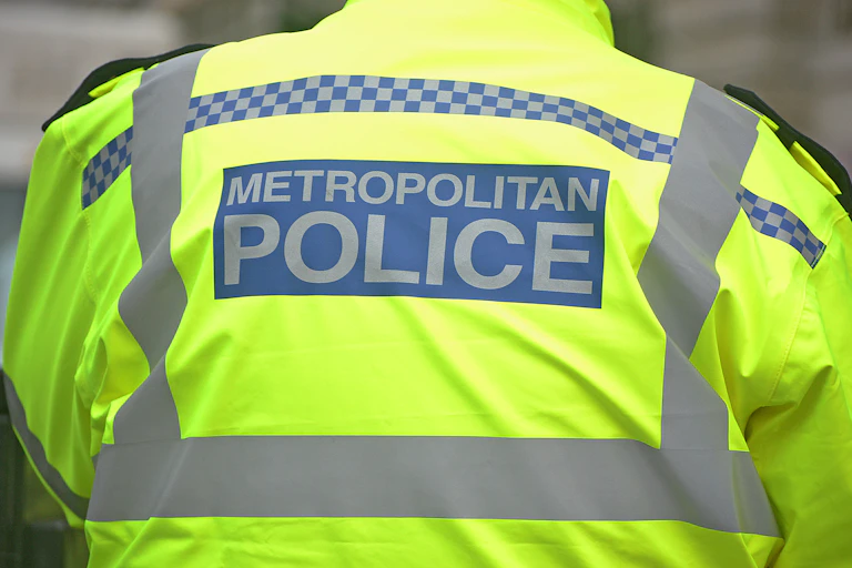 A police officer in a high-vis vest seen from behind, tightly cropped.