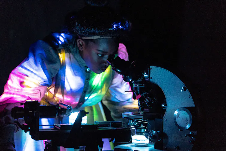 A woman seen peering into a microscope.