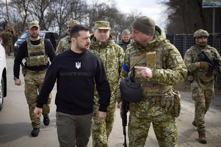 Ukraine's president Volodymyr Zelensky with a group of soldiers in military uniform.