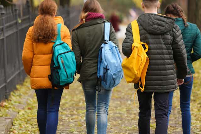 A group of young people carrying backpacks walking together.