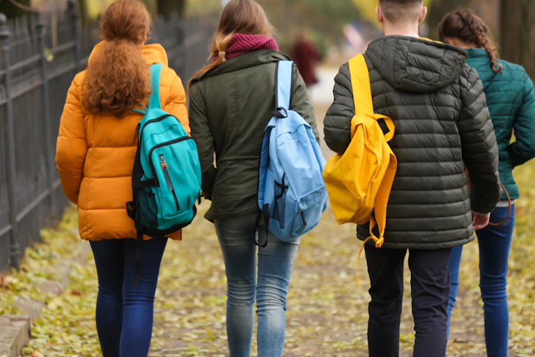 A group of young people carrying backpacks walking together.