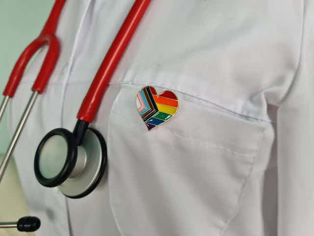 Silhouette of doctor in white coat with stethoscope and LGBTQ pin on pocket