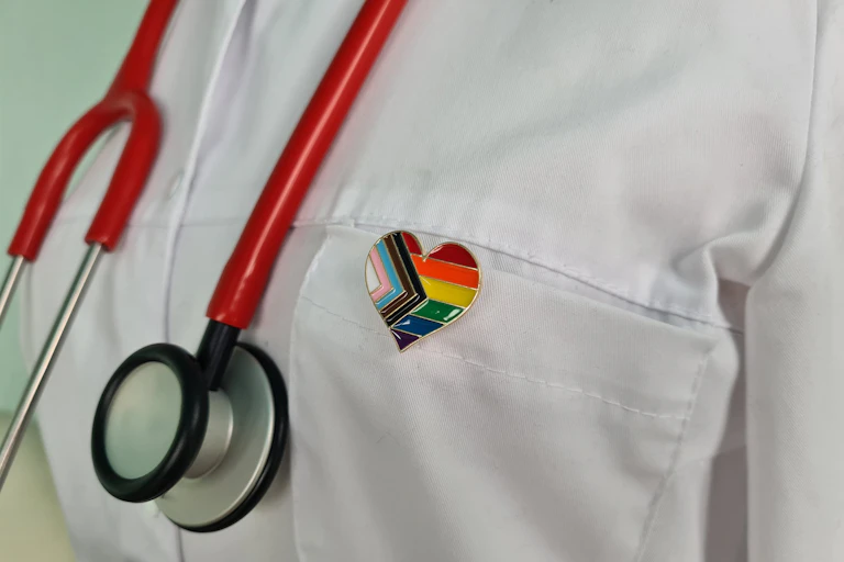 Silhouette of doctor in white coat with stethoscope and LGBTQ pin on pocket