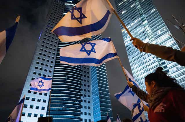 Manifestantes sostienen banderas de Israel.