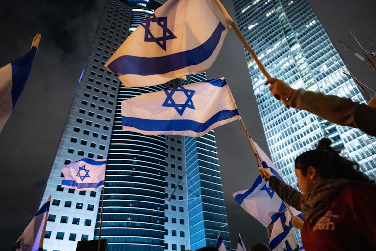 Manifestantes sostienen banderas de Israel.