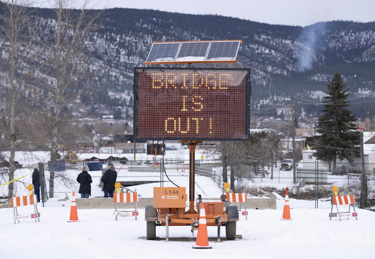 A sign that reads: bridge is out on a snowy road.