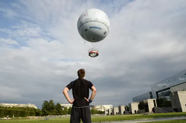 un homme regarde la montgolfière du parc andré citroën