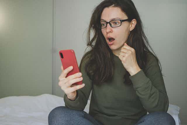 Woman looking at her phone shocked and appalled