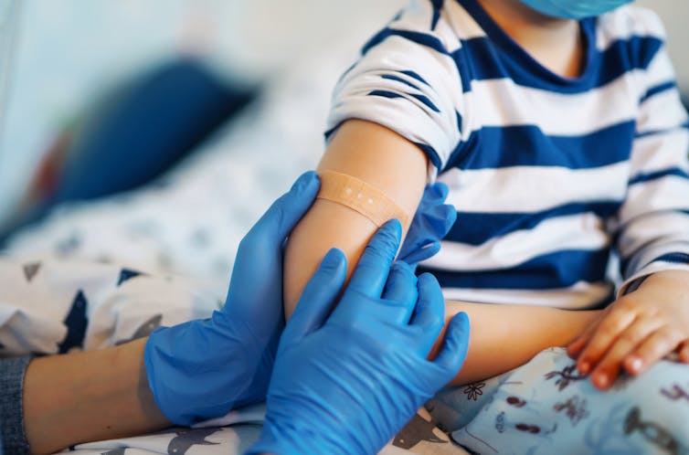 Health worker puts bandaid on child's arm after vaccination
