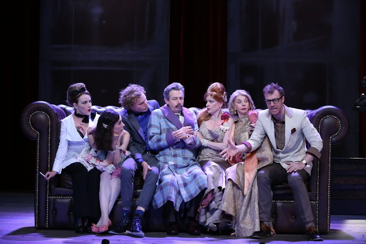 Actors sitting on a couch.