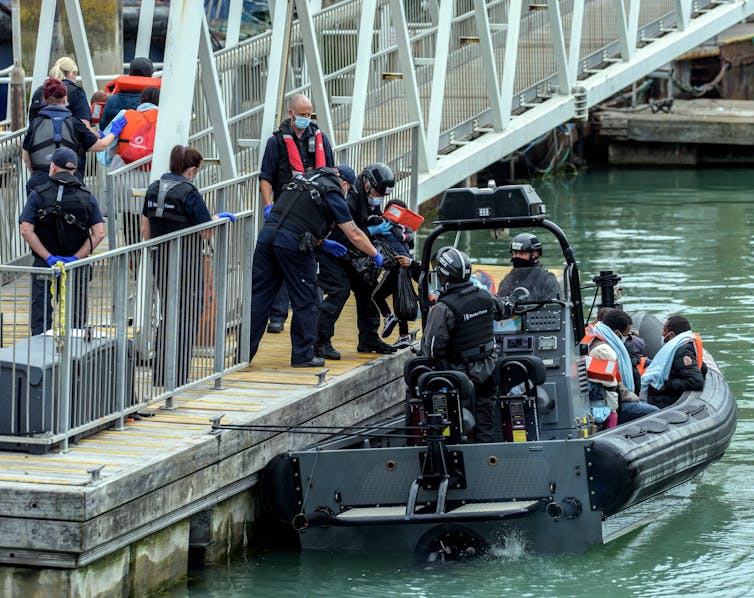 A Border Force boat carrying several migrants and Border Force officials pulls up to a dock in Dover