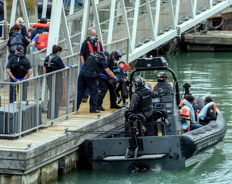 A Border Force boat carrying several migrants and Border Force officials pulls up to a dock in Dover