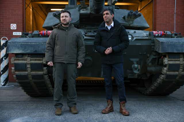 Ukrainian president Volodymyr Zelensky and UK prime minister Rishi Sunak stand in front of a Challenger II tank.