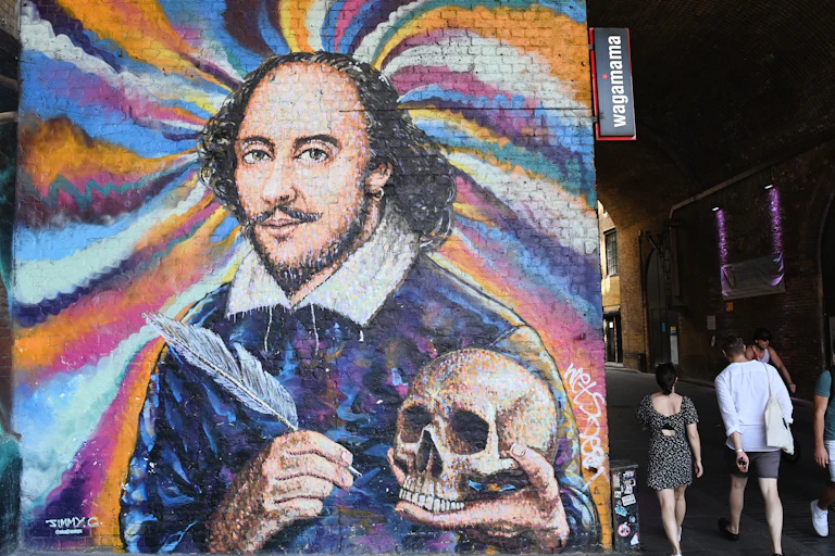 A mural of Shakespeare painted over a whirlwind of colours. He holds a feather quill and a skull.