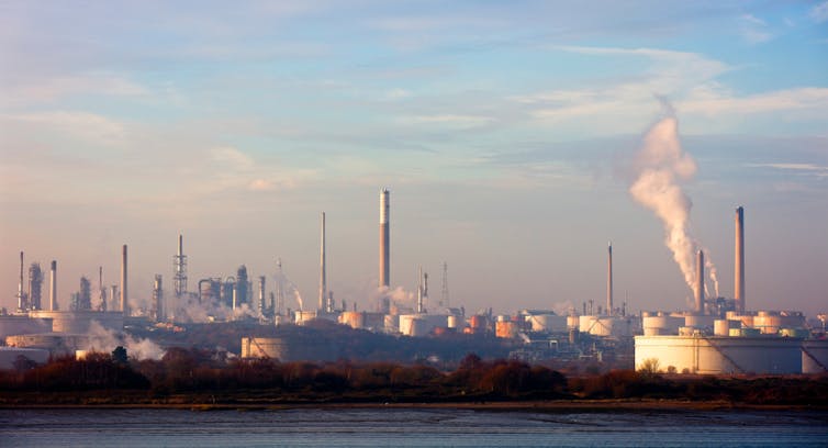 Uma cena industrial com chaminés e tanques de armazenamento.