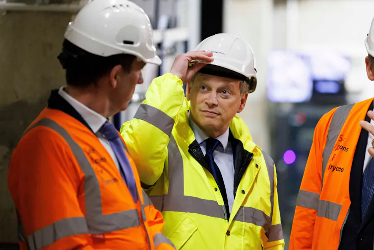 Man in hi-vis holds hard hat