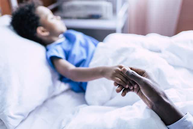 A boy lies in a hospital bed.
