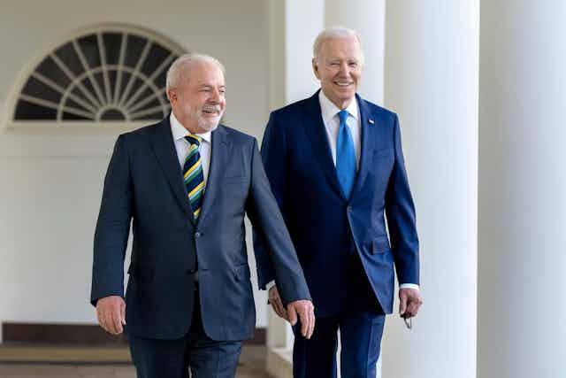 Brazil's president Lula wearing a striped tie and blue suit walks ahead of US president Joe Biden.