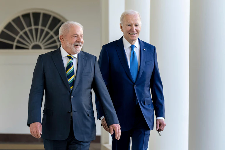 Brazil's president Lula wearing a striped tie and blue suit walks ahead of US president Joe Biden.