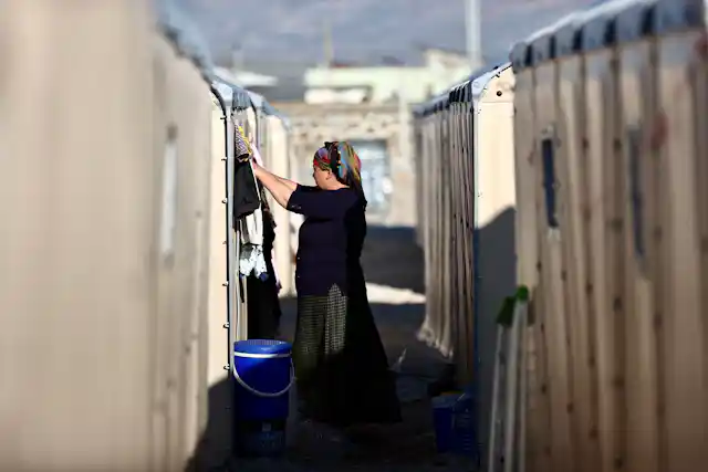 A woman wearing dark clothing stands in between two rows of white tents.