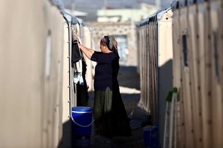 A woman wearing dark clothing stands in between two rows of white tents.