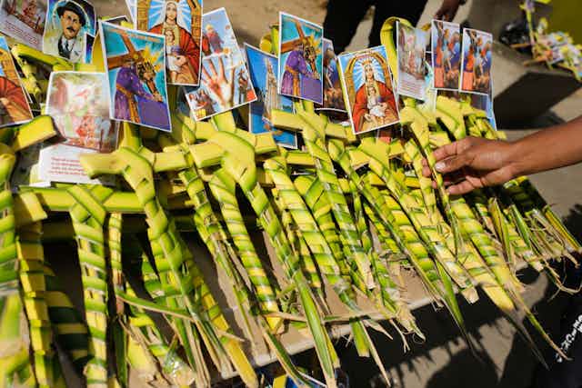 Piles of crosses made out of palm leaves with small religious pictures of affixed to each one.