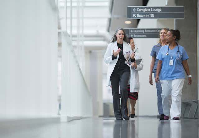 A group of female doctors walking down a hallway.