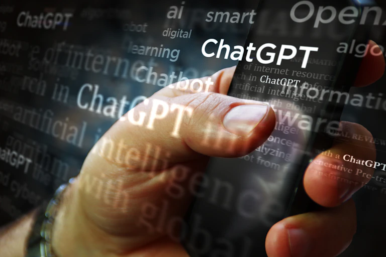 A hand holding a cellphone with words like 'AI, ChatGPT, smart and artificial intelligence' superimposed over it