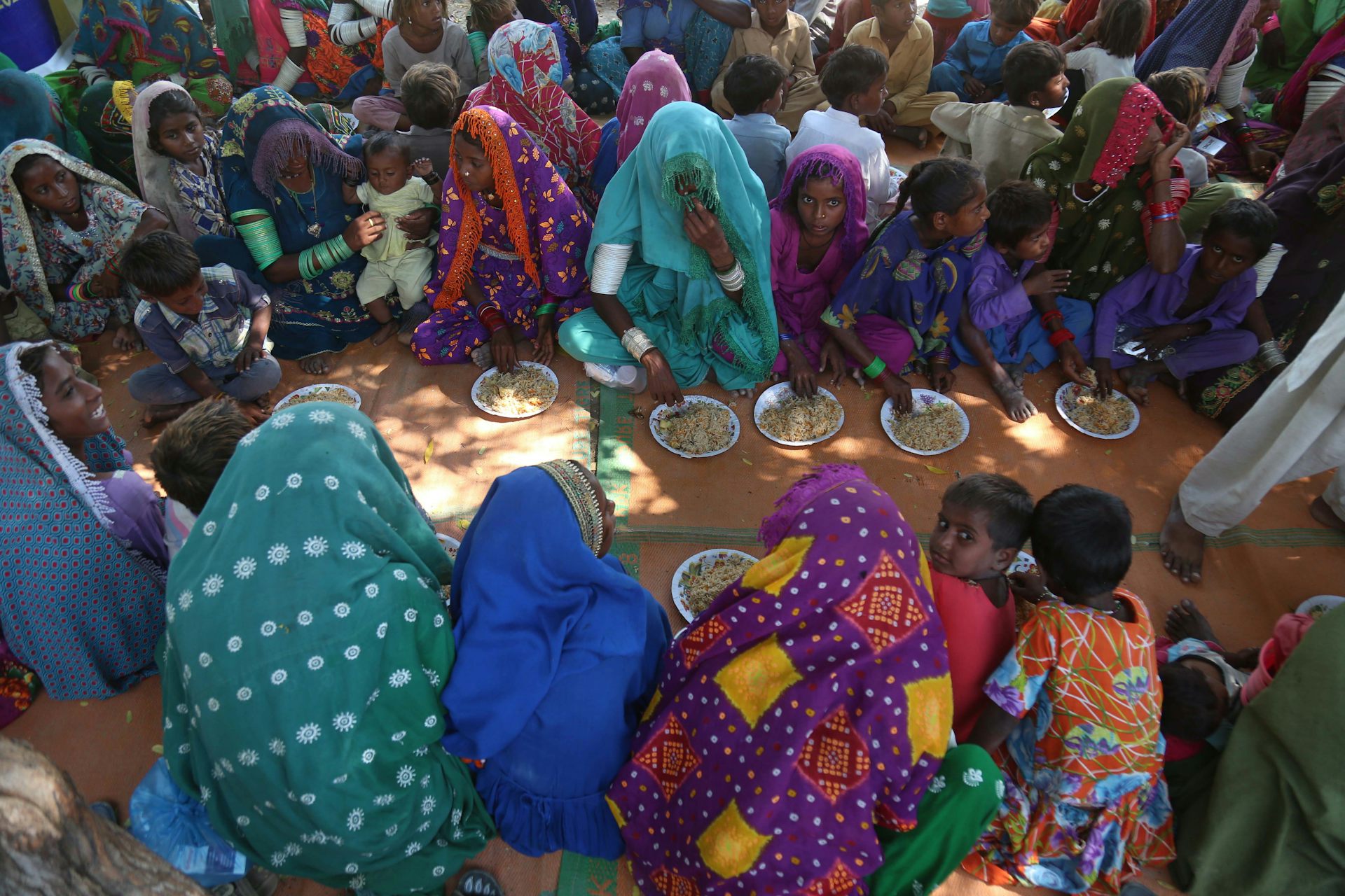 people sit on ground with plates of food