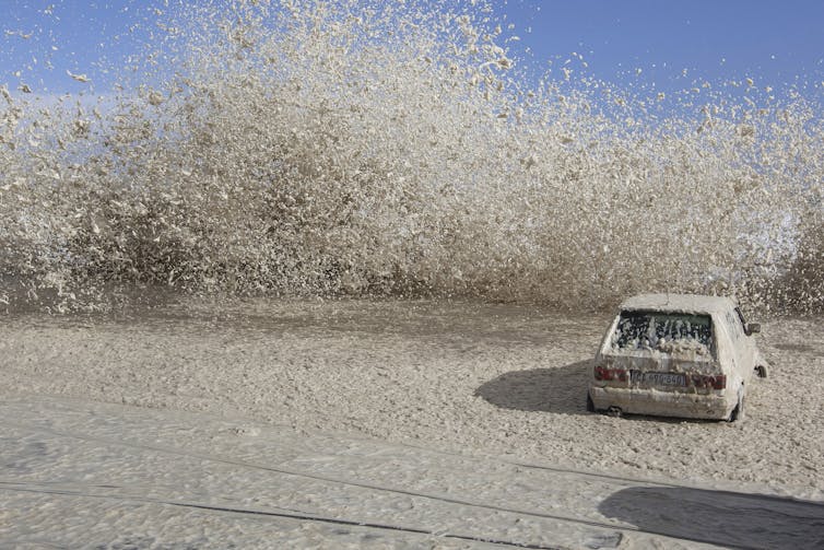 foamy ocean crashes onto foreshore and car