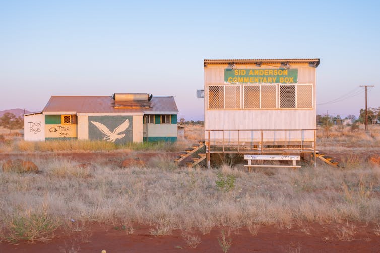 A commentary box at Papunya Oval, which is surrounded by overgrown weeds.