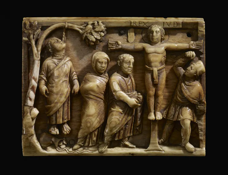 Judas hangs from tree; below him the purse from which fall pieces of silver; to the right Christ is nailed by the hands only to the cross