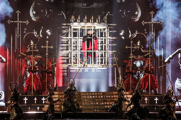 Madonna performs, surrounded by crosses.