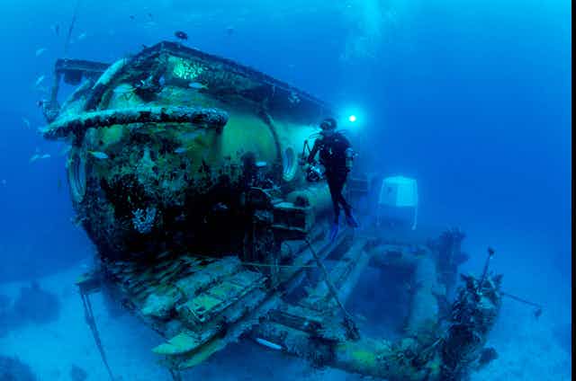 A photo of a diver in front of the Aquarius Habitat, an underwater habitat used by researchers.