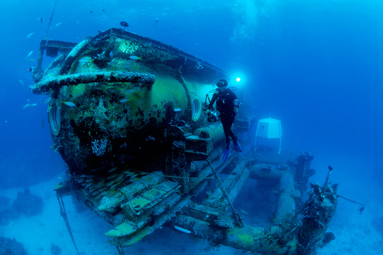 A photo of a diver in front of the Aquarius Habitat, an underwater habitat used by researchers.