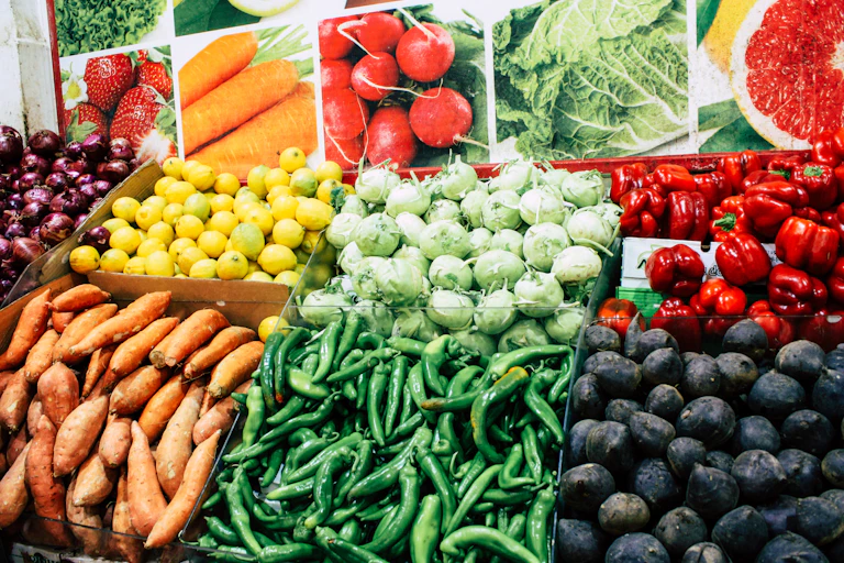 Photo shows peppers, sweet potatoes, lemons plus other vegetables on a stall.