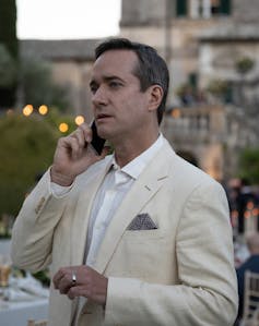 A man in a smart cream suit on the phone.