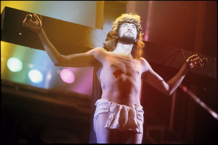 A man playing Jesus in a play in front of a cross.