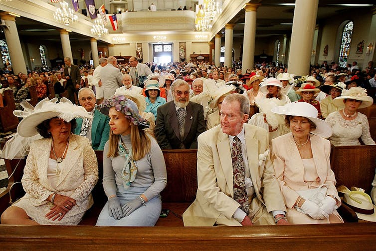 An older photo of a church full of worshippers, most of the women in fancy hats.