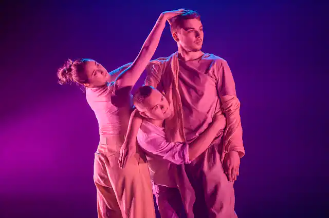 Three dancers bathed in pink.