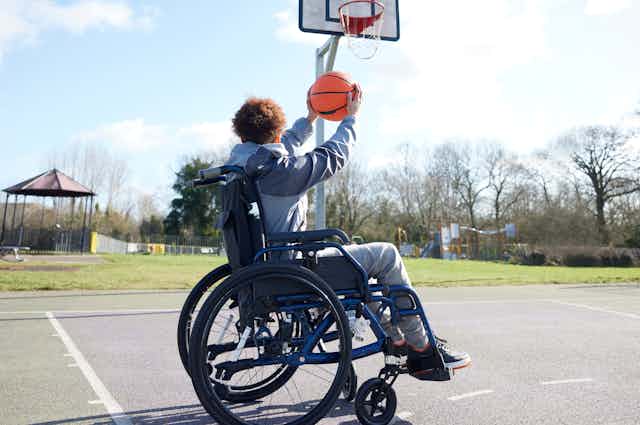 Girl playing basketball outside using wheelchair