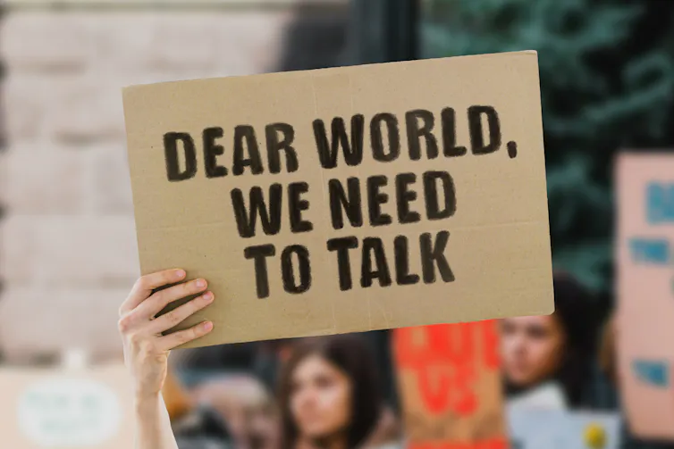 A person holding up a banner that reads:
