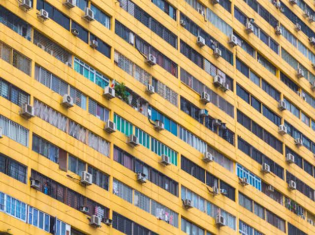 An apartment building exterior dotted with air-conditioner units and windows.